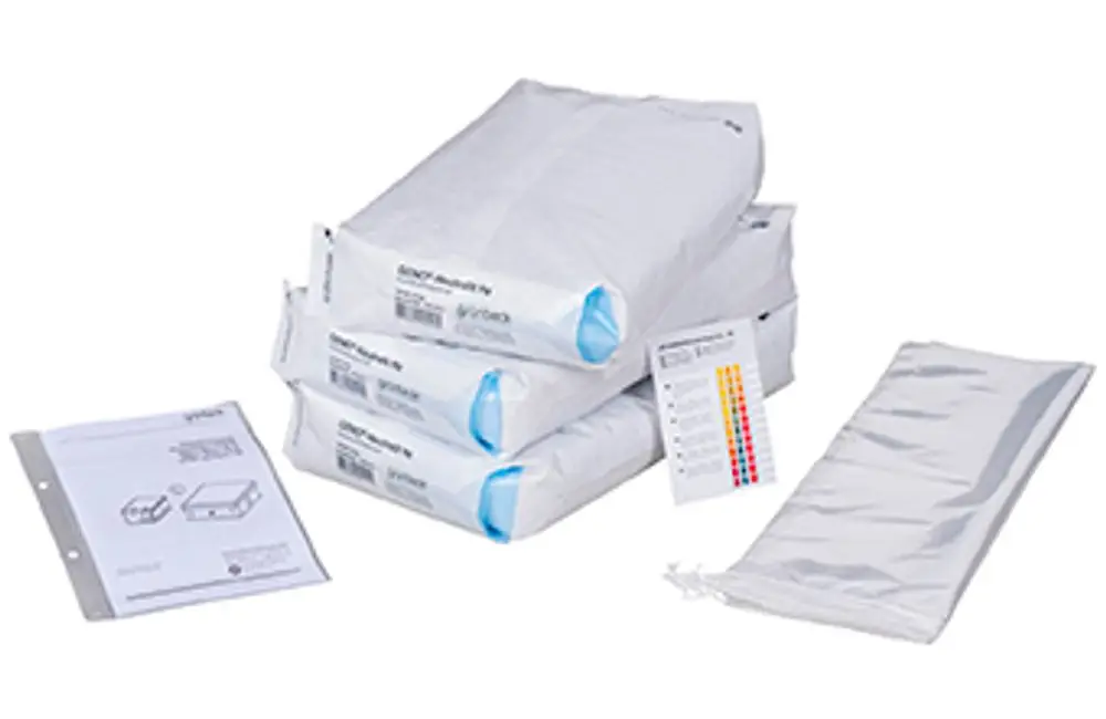 Wartungsset von Grünbeck bestehend aus mehreren weißen, in Folie verpackten Komponenten und einer Anleitung in einem Ordner, neben einer transparenten Tasche.
